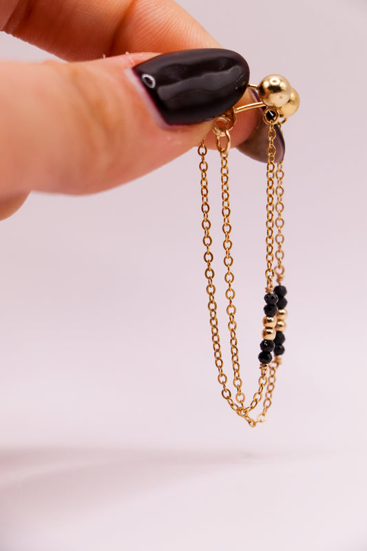 Élégantes boucles d'oreilles en or laminé 14k, ornées de spinelles noirs brillants qui ajoutent une touche de sophistication et de mystère. Le design épuré et moderne met en valeur la profondeur et l'éclat des pierres, créant une pièce idéale pour sublimer une tenue de jour comme de soirée.