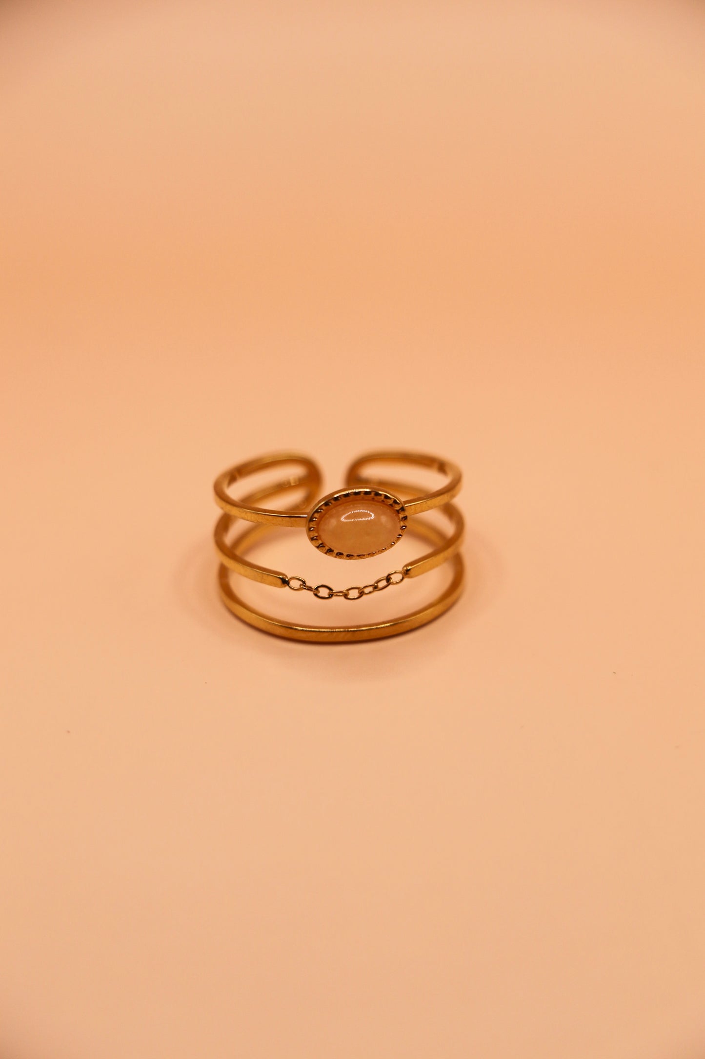 Bague dorée en acier inoxydable à trois anneaux avec médaillon central et fine chaîne décorative