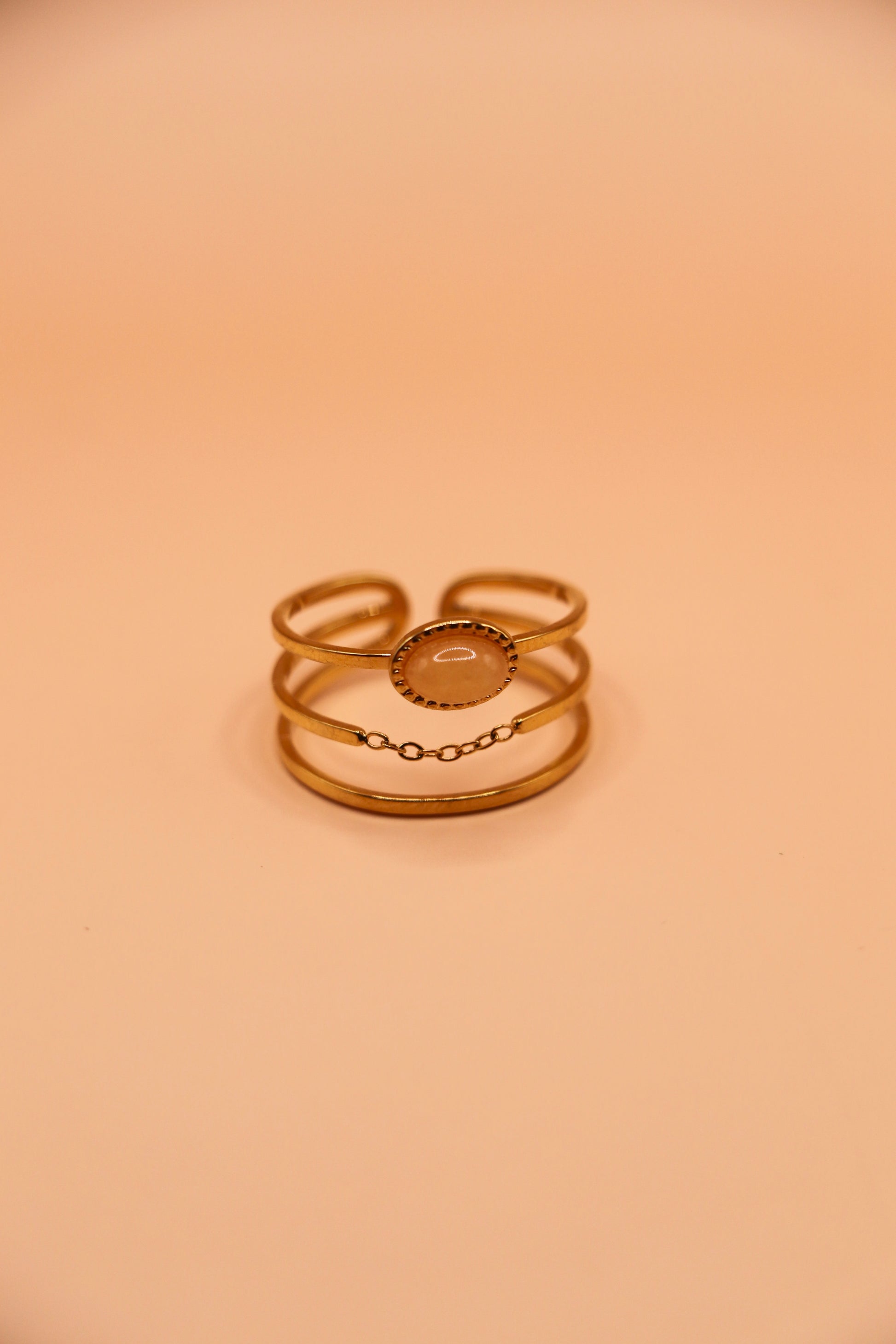 Bague dorée en acier inoxydable à trois anneaux avec médaillon central et fine chaîne décorative