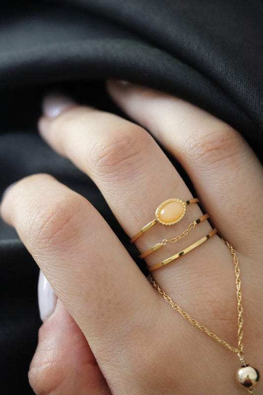 Bague dorée en acier inoxydable à trois anneaux avec médaillon central et fine chaîne décorative