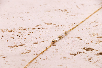Bracelet en or laminé 14K avec deux perles d’eau douce naturelles encadrées de perles dorées striées – bijou fin, lumineux, fait main en France.