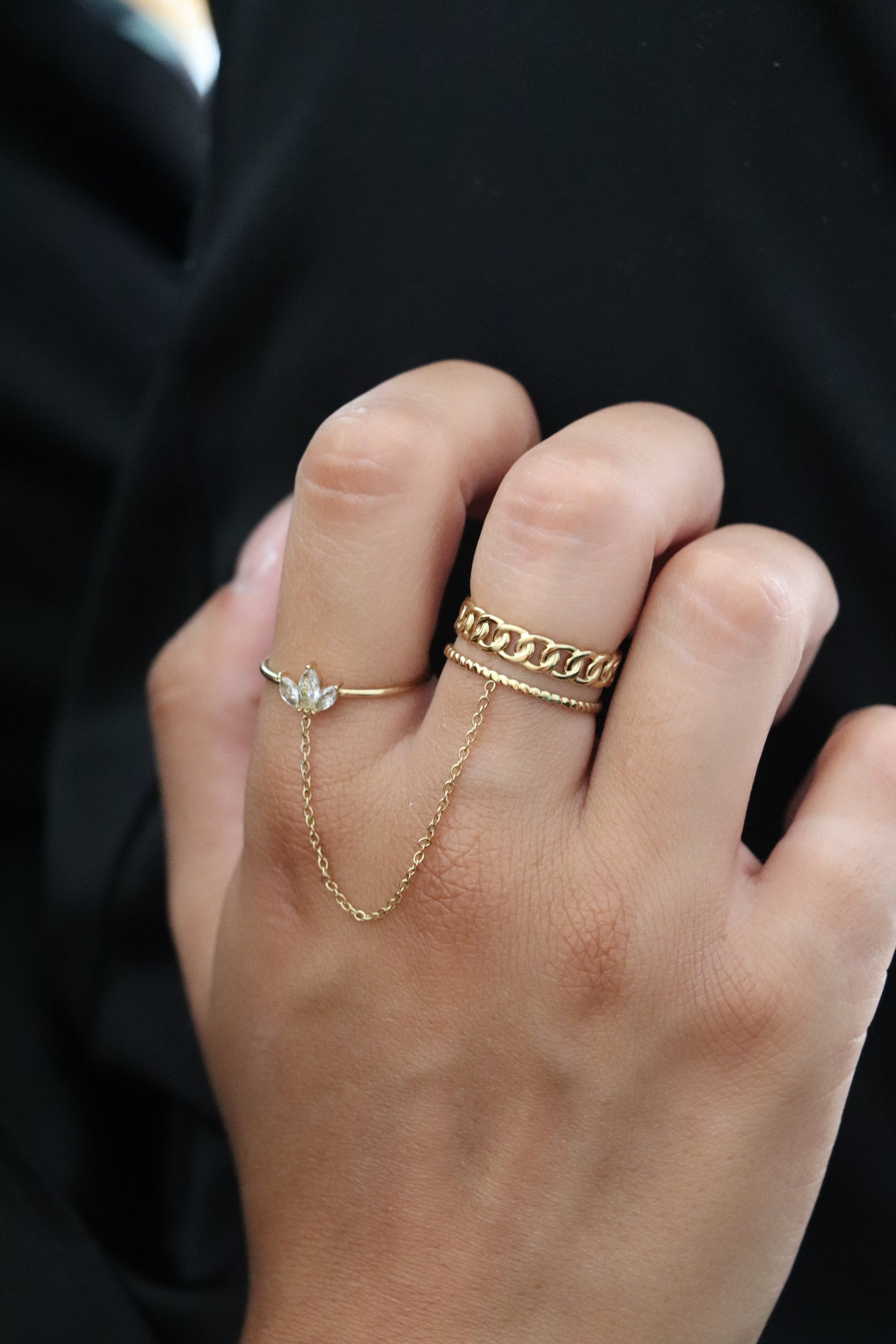 Main portant une bague chaîne en acier inoxydable doré avec zircons blancs – bijou tendance et original pour femme.