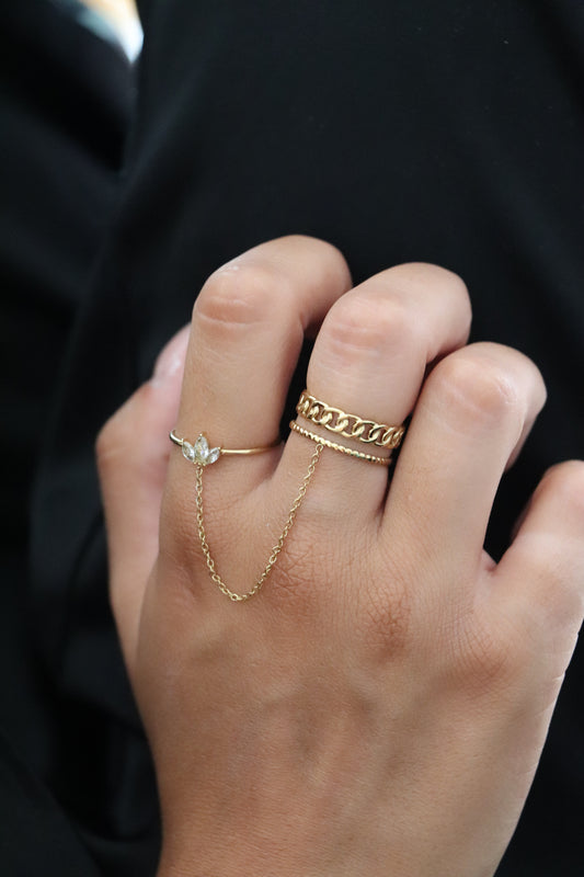 Main portant une bague chaîne en acier inoxydable doré avec zircons blancs – bijou tendance et original pour femme.